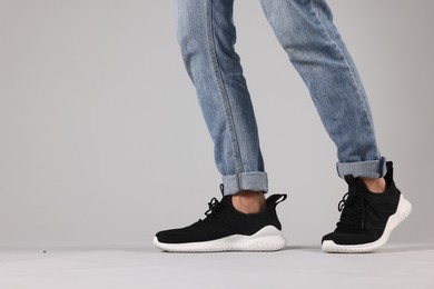 Photo of Man wearing pair of black sneakers indoors, closeup. Space for text