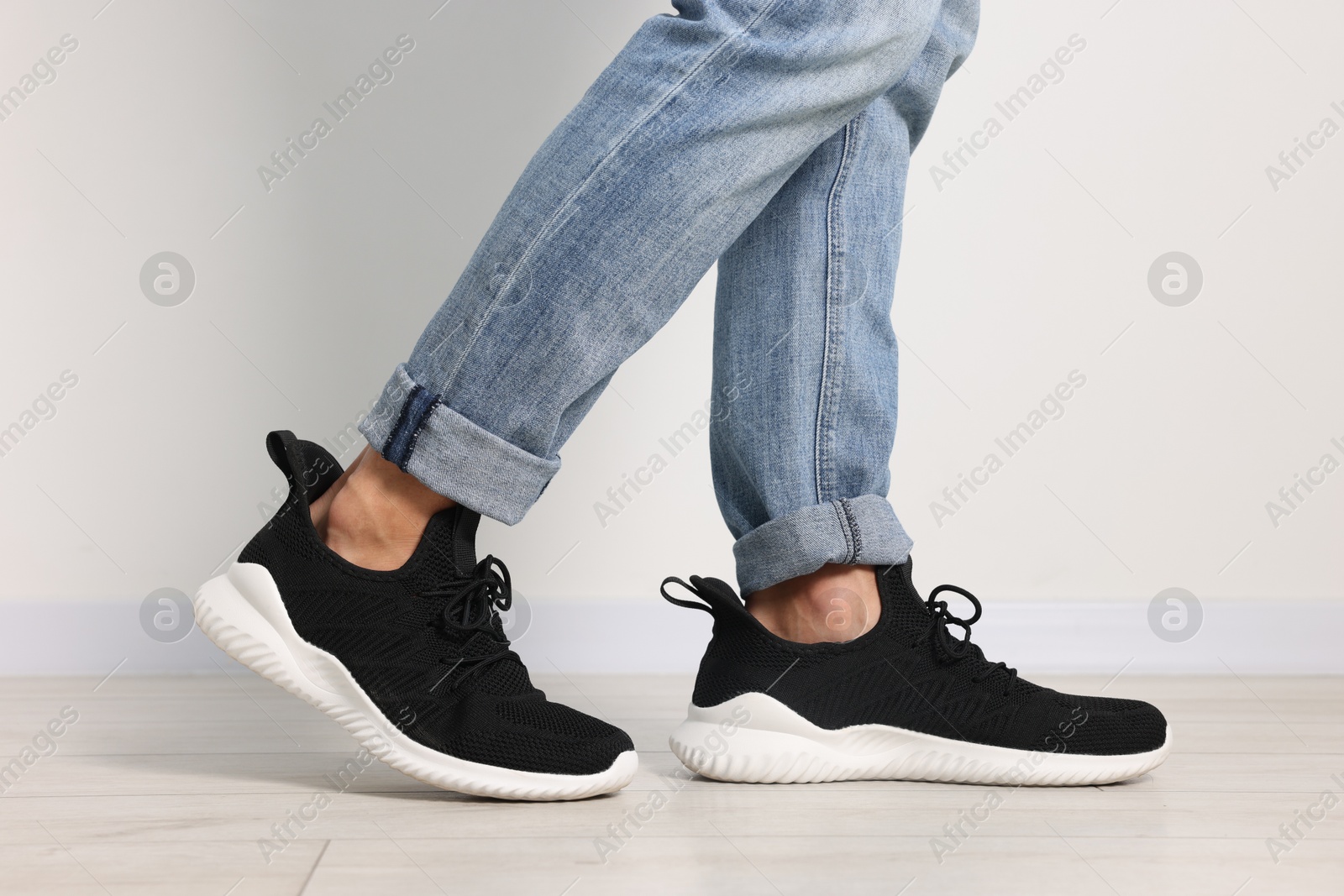 Photo of Man wearing pair of black sneakers indoors, closeup