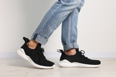 Photo of Man wearing pair of black sneakers indoors, closeup