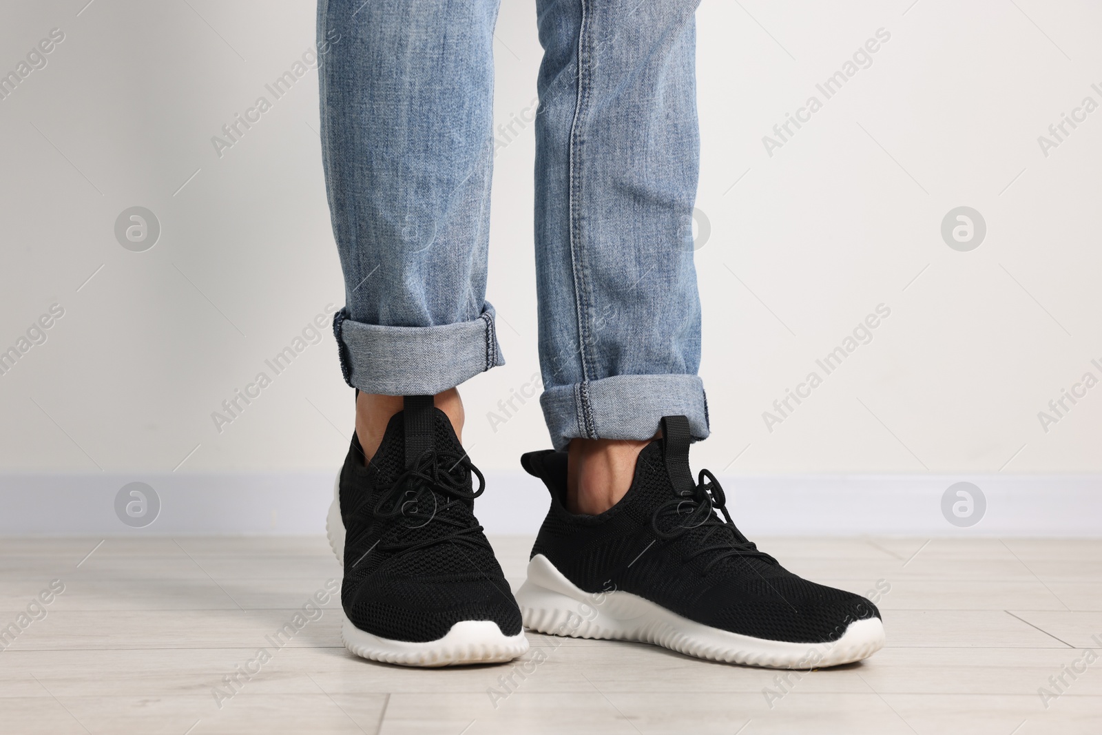 Man wearing pair of black sneakers indoors, closeup Photo of Man wearing pair of black sneakers indoors, closeup