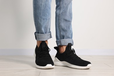 Photo of Man wearing pair of black sneakers indoors, closeup