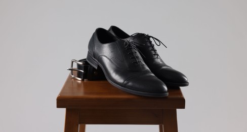 Photo of Pair of black leather shoes on stool against light background