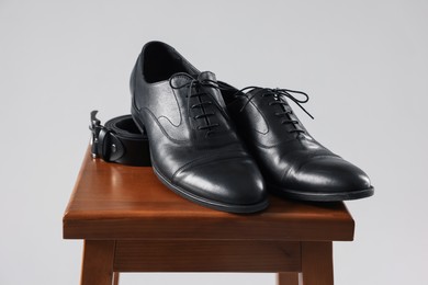 Photo of Pair of black leather shoes on stool against light background
