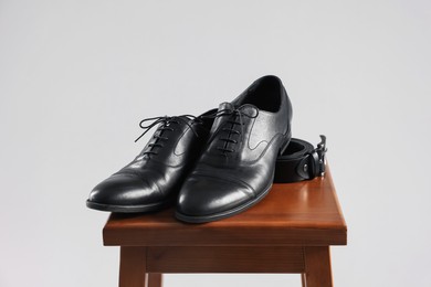 Photo of Pair of black leather shoes on stool against light background