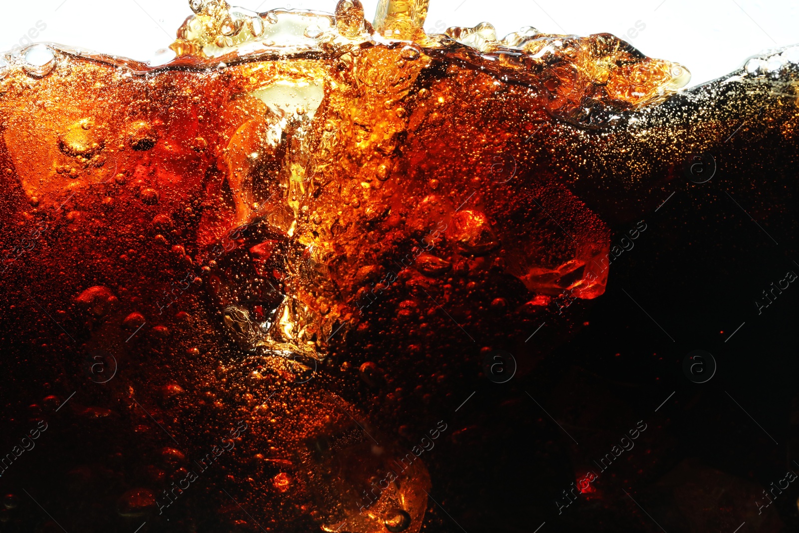 Pouring refreshing cola into glass with ice on white background, closeup Photo of Pouring refreshing cola into glass with ice on white background, closeup