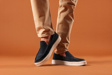 Photo of Man wearing pair of dark blue shoes on brown background, closeup