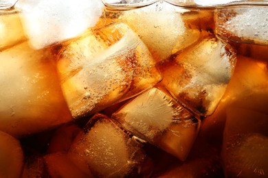 Photo of Refreshing cola with ice as background, macro view