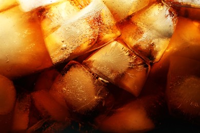 Photo of Refreshing cola with ice as background, macro view