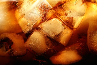 Photo of Refreshing cola with ice as background, macro view