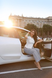 Photo of Woman getting out of modern car outdoors