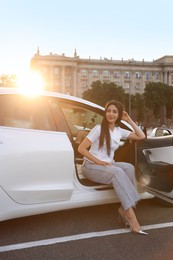 Photo of Woman getting out of modern car outdoors
