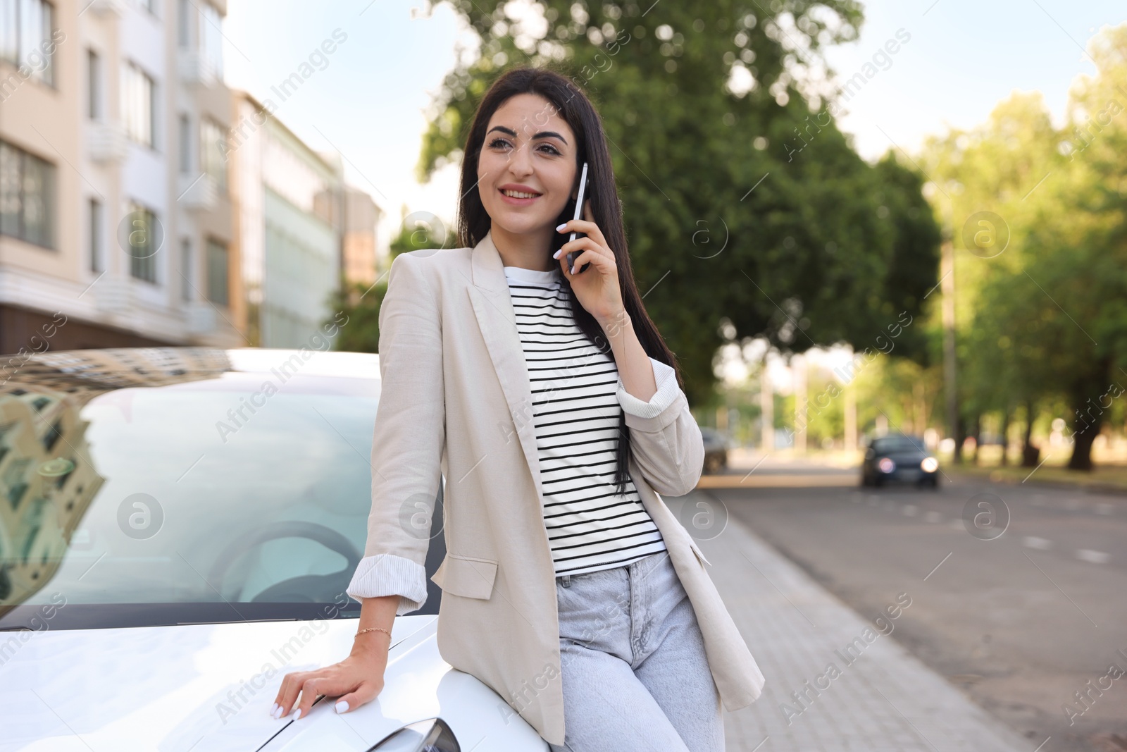 Photo of Beautiful woman talking on smartphone near car outdoors