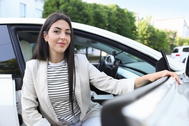 Photo of Woman getting out of modern car outdoors