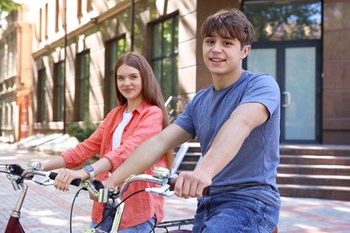 Photo of Teenage girl and boy riding bicycles on city street