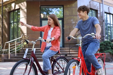 Photo of Teenage girl and boy riding bicycles on city street