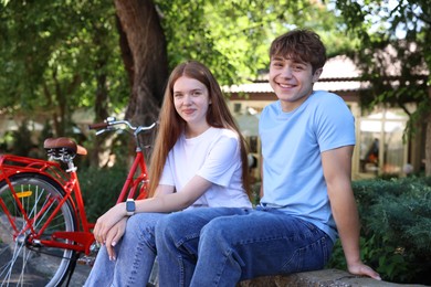 Photo of Teenage girl and boy near bicycle outdoors