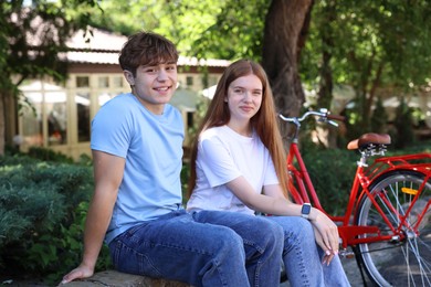 Photo of Teenage girl and boy near bicycle outdoors