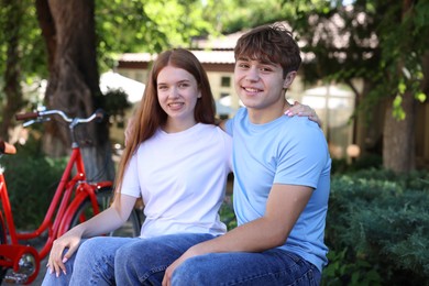 Photo of Teenage girl and boy near bicycle outdoors