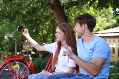 Photo of Teenage girl and boy with bicycles taking selfie on city street