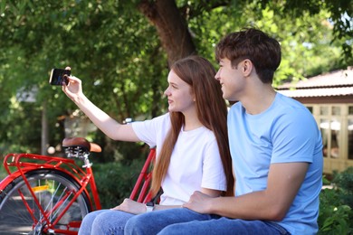 Photo of Teenage girl and boy with bicycles taking selfie on city street
