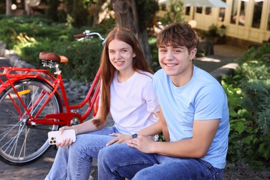 Photo of Teenage girl and boy near bicycle outdoors