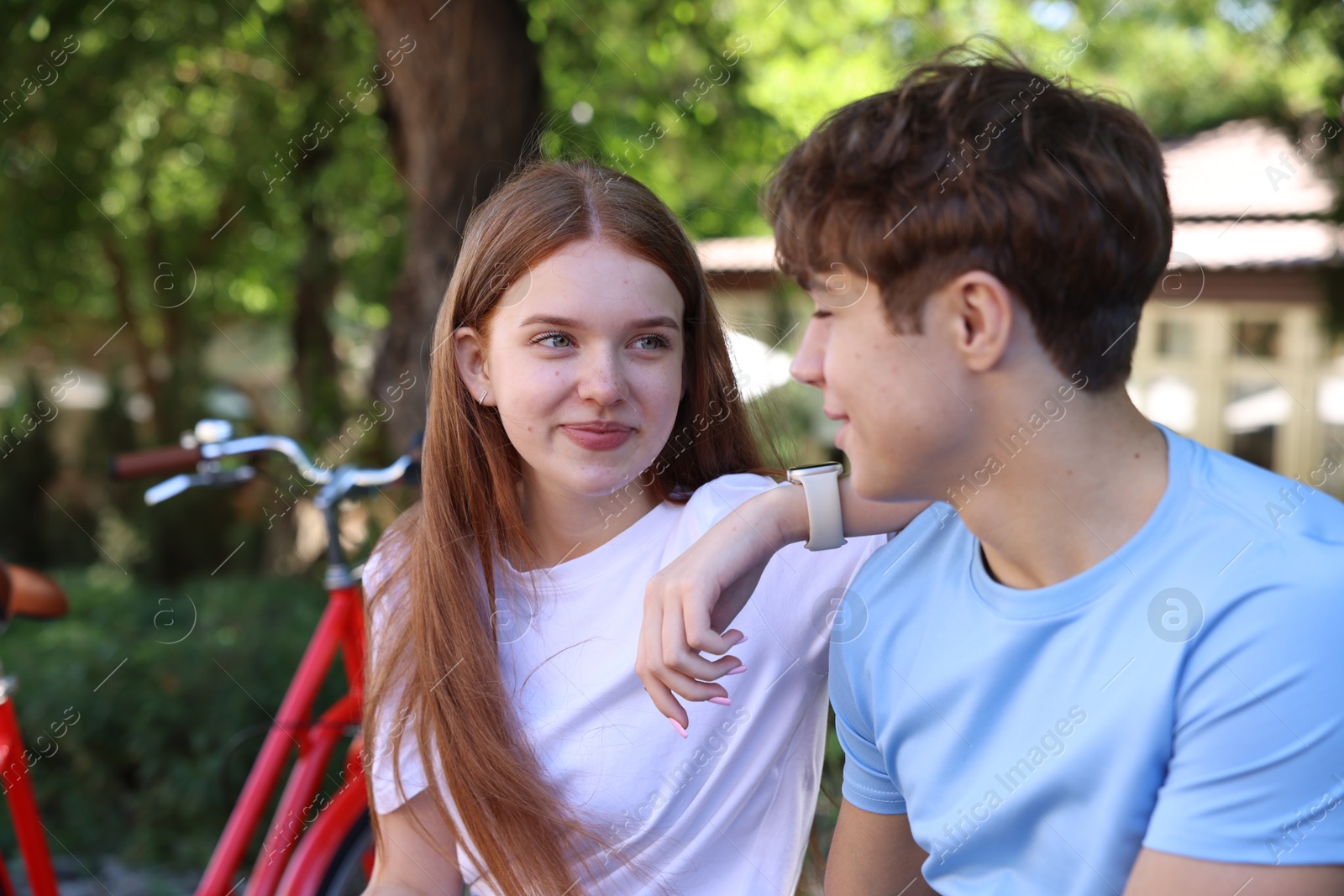 Teenage girl and boy near bicycle outdoors Photo of Teenage girl and boy near bicycle outdoors