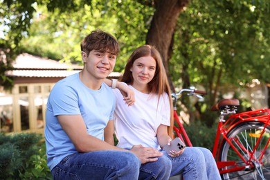 Photo of Teenage girl and boy near bicycle outdoors