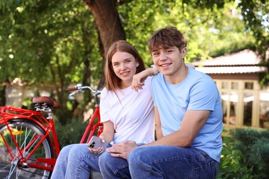 Photo of Teenage girl and boy near bicycle outdoors