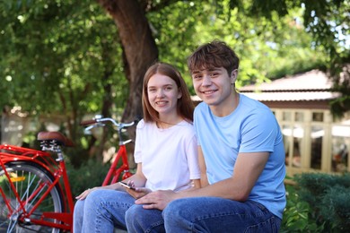Photo of Teenage girl and boy near bicycle outdoors