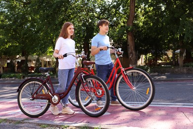 Photo of Teenage girl and boy with bicycles on city street