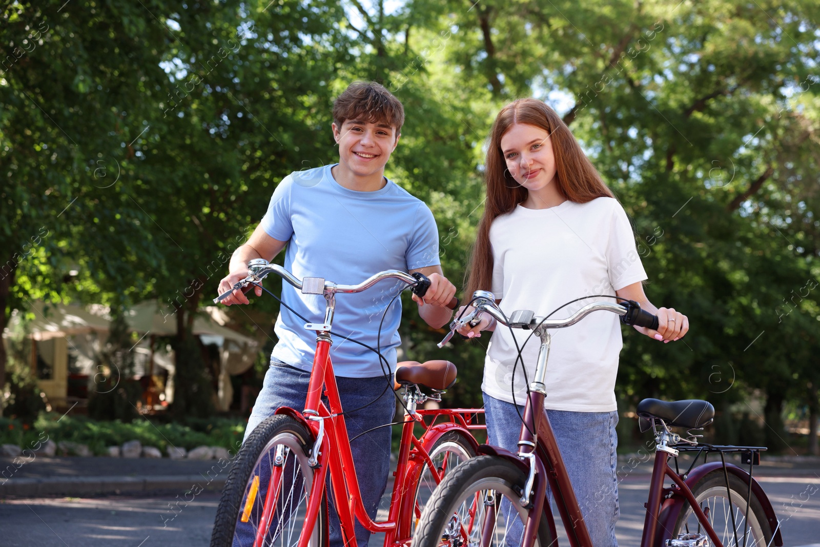 Teenage girl and boy with bicycles on city street Photo of Teenage girl and boy with bicycles on city street