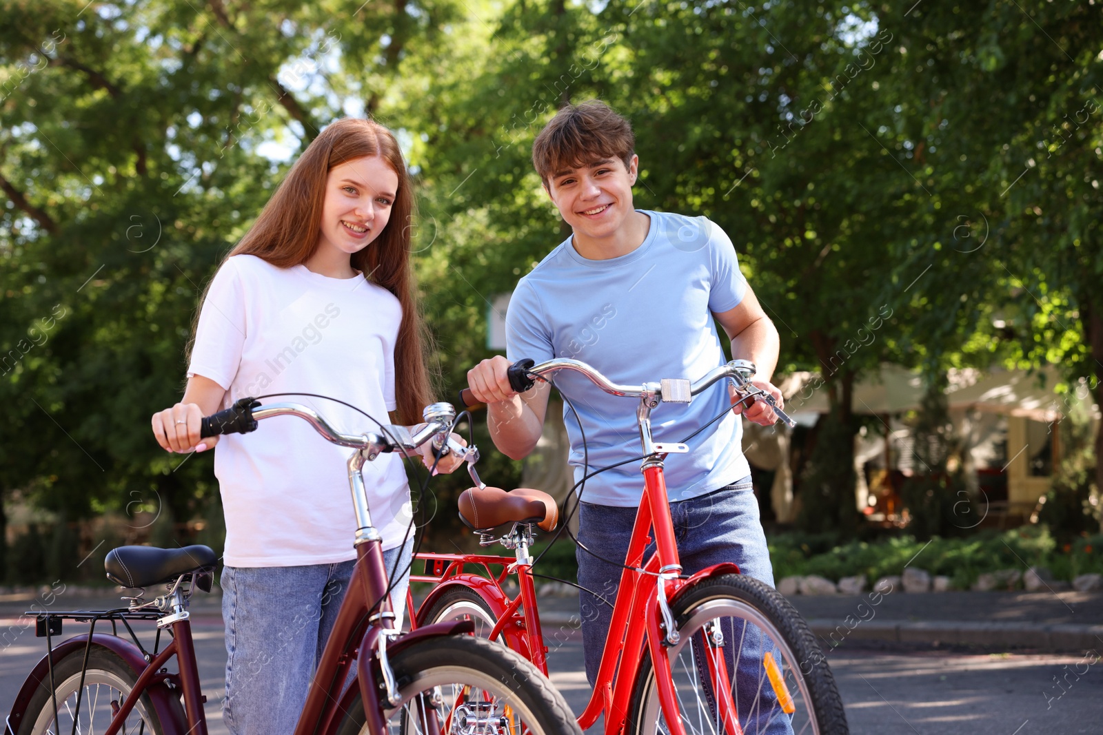 Photo of Teenage girl and boy with bicycles on city street