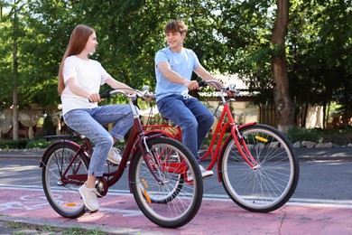 Photo of Teenage girl and boy riding bicycles on city street