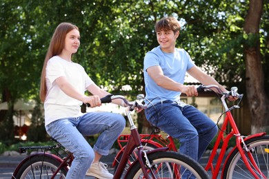 Photo of Teenage girl and boy riding bicycles on city street
