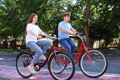 Photo of Teenage girl and boy riding bicycles on city street