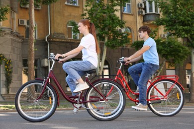 Photo of Teenage girl and boy riding bicycles on city street
