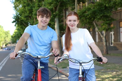 Photo of Teenage girl and boy riding bicycles on city street