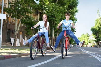 Photo of Teenage girl and boy riding bicycles on city street