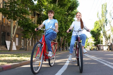 Photo of Teenage girl and boy riding bicycles on city street