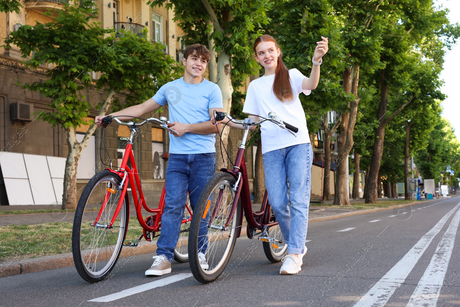 Teenage girl and boy with bicycles on city street Photo of Teenage girl and boy with bicycles on city street