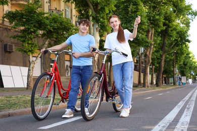 Photo of Teenage girl and boy with bicycles on city street