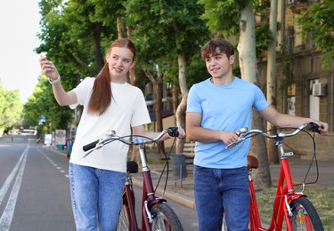 Photo of Teenage girl and boy with bicycles on city street