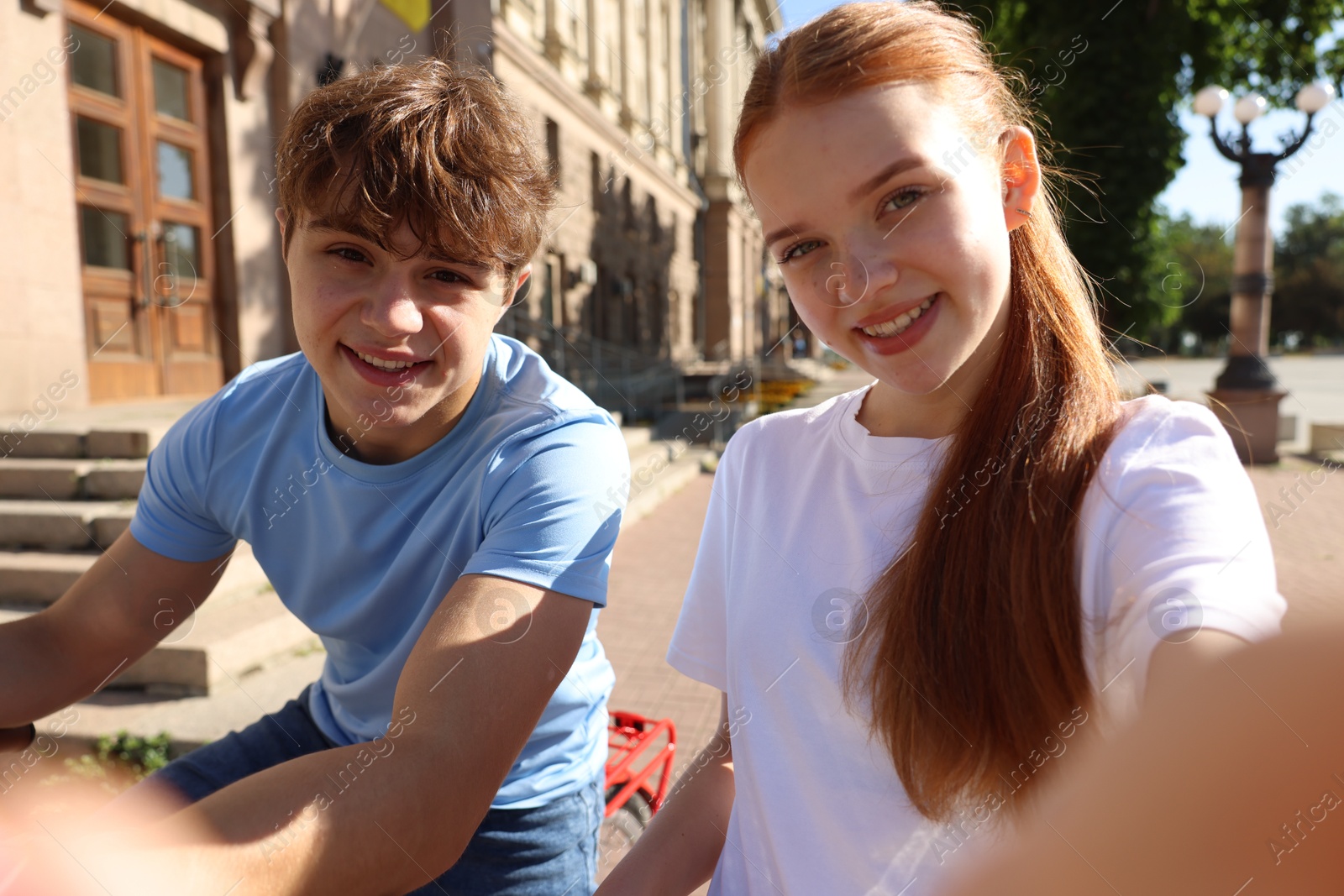 Photo of Teenage girl and boy with bicycles taking selfie on city street