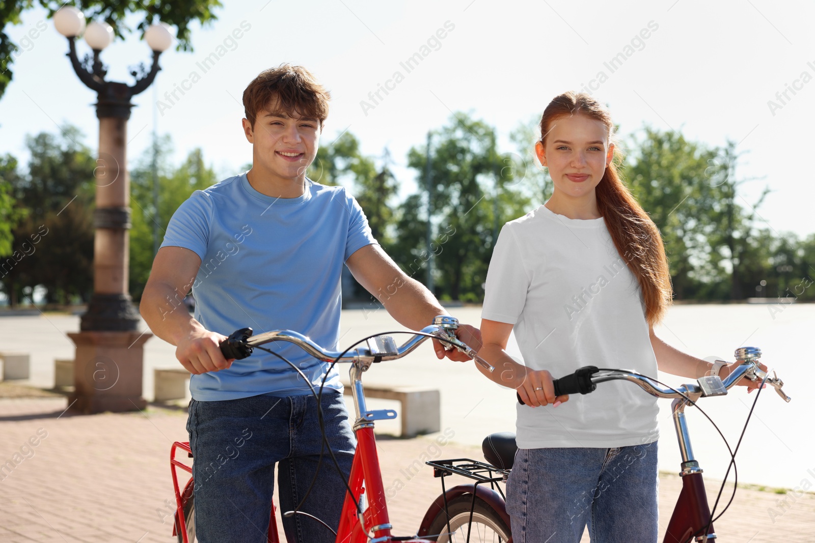 Teenage girl and boy riding bicycles on city street Photo of Teenage girl and boy riding bicycles on city street
