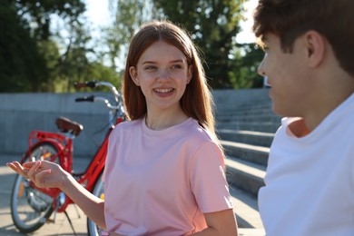 Photo of Teenage girl and boy sitting on stairs near bicycle on city street
