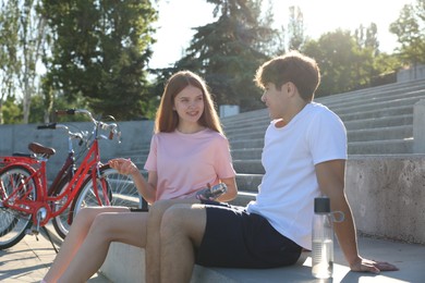 Photo of Teenage girl and boy sitting on stairs near bicycles on city street