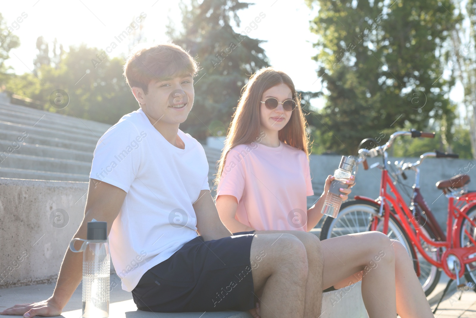 Teenage girl and boy sitting on stairs near bicycles on city street Photo of Teenage girl and boy sitting on stairs near bicycles on city street
