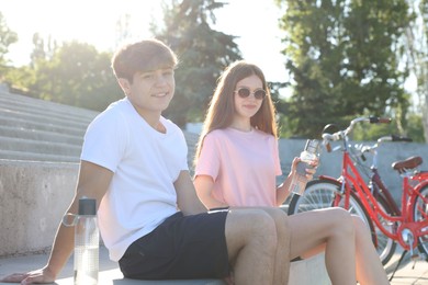 Photo of Teenage girl and boy sitting on stairs near bicycles on city street
