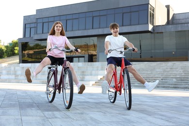 Photo of Teenage girl and boy riding bicycles on city street