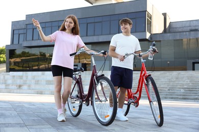 Photo of Teenage girl and boy with bicycles on city street